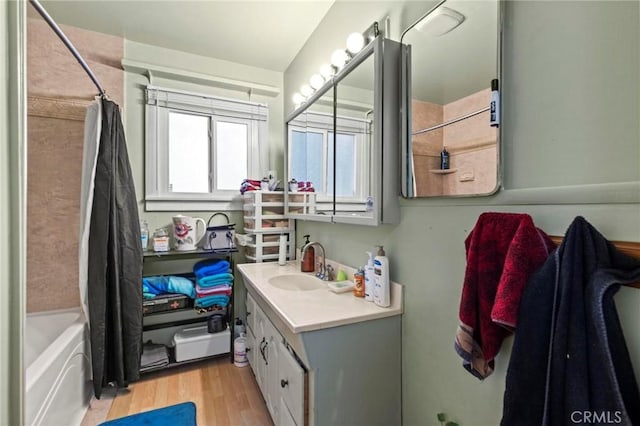 full bath featuring shower / bath combo with shower curtain, wood finished floors, and vanity