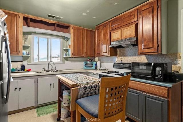 kitchen with black microwave, under cabinet range hood, a sink, visible vents, and open shelves