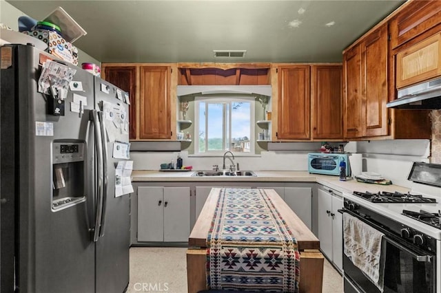 kitchen with light countertops, gas stove, a sink, under cabinet range hood, and stainless steel fridge with ice dispenser