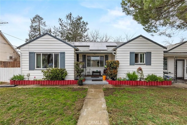 view of front of home featuring a front yard, fence, and solar panels