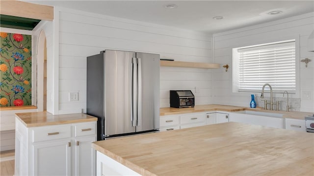 kitchen featuring a sink, open shelves, white cabinetry, freestanding refrigerator, and wooden counters