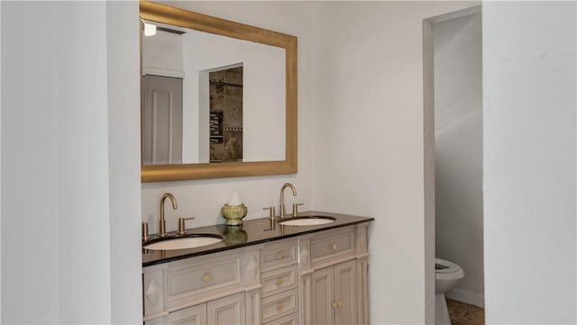 bathroom featuring double vanity, toilet, and a sink