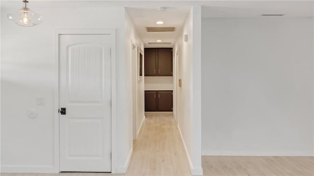 corridor with baseboards, visible vents, and light wood-type flooring