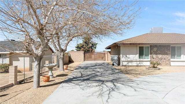 view of side of property featuring a gate, fence, driveway, and stucco siding