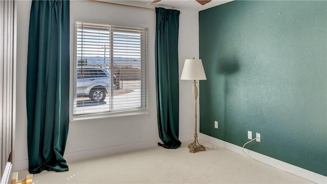 unfurnished room featuring a textured wall, baseboards, and ceiling fan