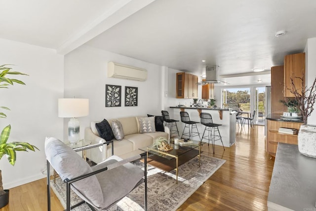 living area with baseboards, an AC wall unit, and wood finished floors