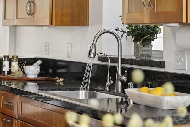 kitchen with tasteful backsplash, dark countertops, a sink, and brown cabinets