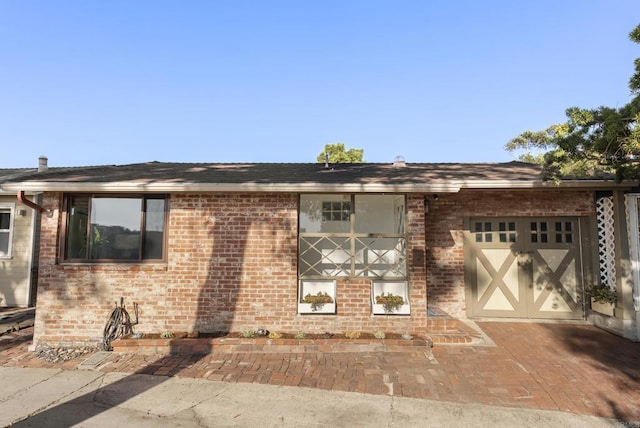 view of front of house featuring a garage, decorative driveway, and brick siding