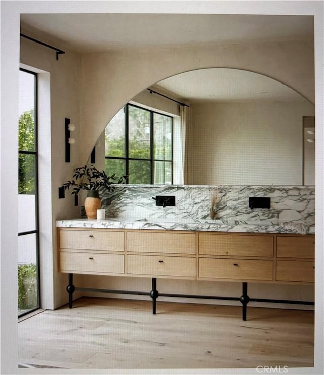 kitchen featuring light wood-type flooring, plenty of natural light, and arched walkways