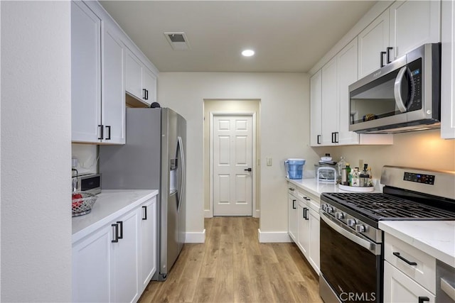 kitchen featuring visible vents, baseboards, light wood-style flooring, white cabinets, and appliances with stainless steel finishes