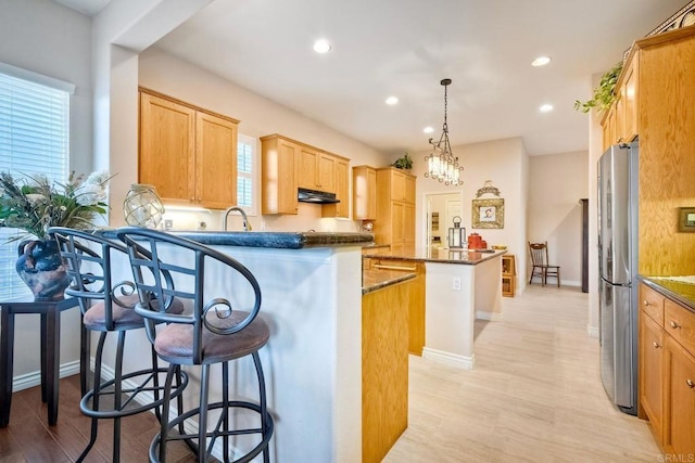kitchen featuring a breakfast bar, freestanding refrigerator, a center island, recessed lighting, and a peninsula
