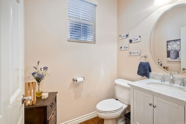 half bath with vanity, toilet, and baseboards