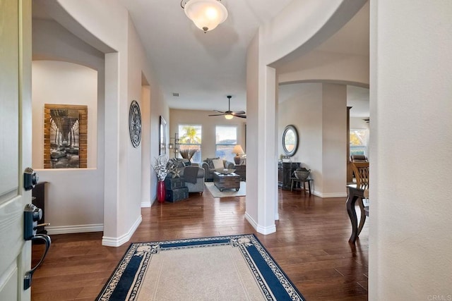 entrance foyer featuring wood finished floors, ceiling fan, baseboards, and arched walkways