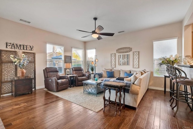 living area with baseboards, visible vents, hardwood / wood-style flooring, and ceiling fan