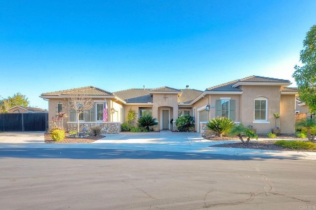 view of front of property with fence, concrete driveway, a tiled roof, an attached garage, and stucco siding