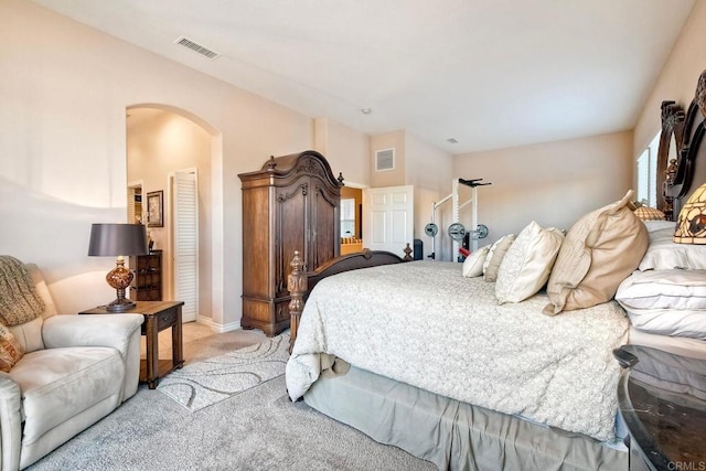 bedroom featuring arched walkways, visible vents, light colored carpet, and baseboards