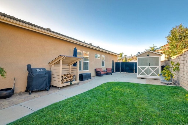 rear view of house with a patio, an outbuilding, a yard, a fenced backyard, and a storage unit