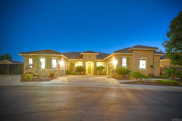 prairie-style home featuring driveway, a gate, stucco siding, and a garage
