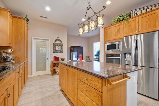 kitchen featuring recessed lighting, dark stone counters, stainless steel appliances, a center island, and visible vents