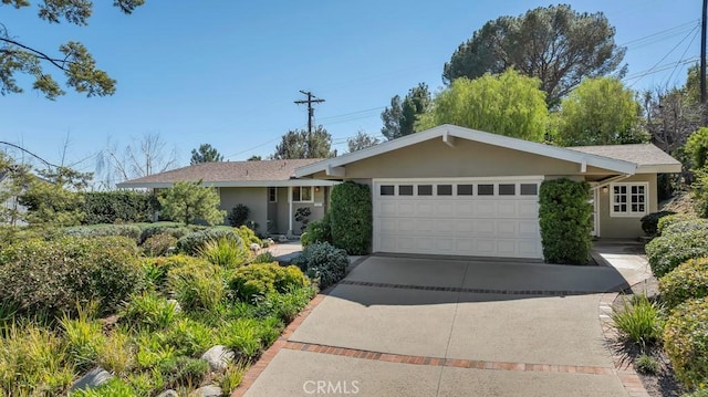 ranch-style home featuring driveway, an attached garage, and stucco siding