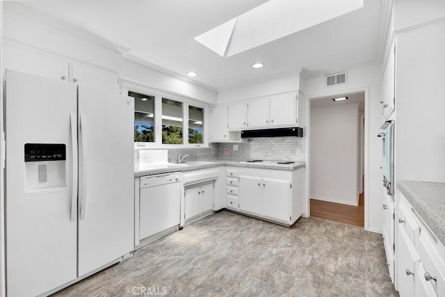 kitchen with under cabinet range hood, white appliances, a skylight, visible vents, and light countertops