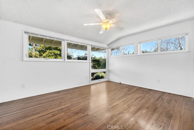 unfurnished room featuring a ceiling fan, vaulted ceiling, a textured ceiling, wood finished floors, and baseboards