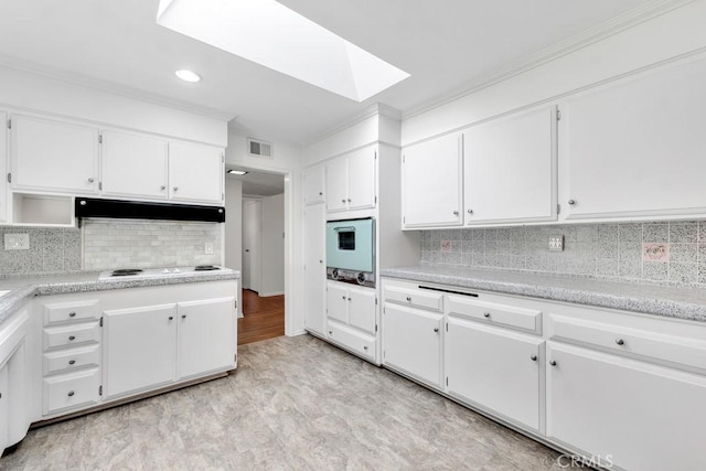 kitchen with light countertops, a skylight, white cabinetry, and under cabinet range hood