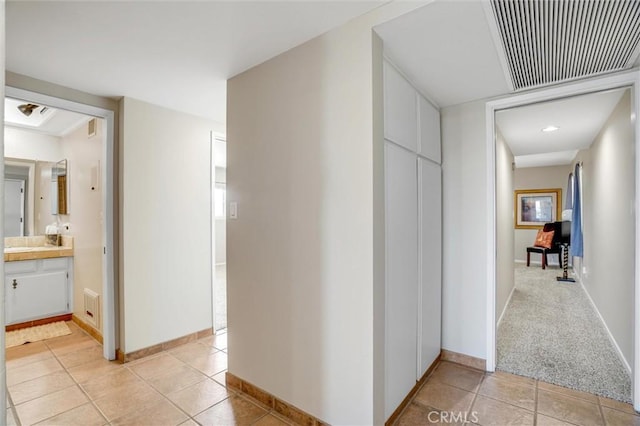 hall with light tile patterned floors, baseboards, and visible vents