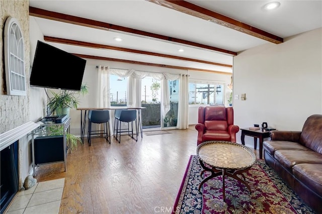 living room featuring light wood-style flooring, beam ceiling, and recessed lighting