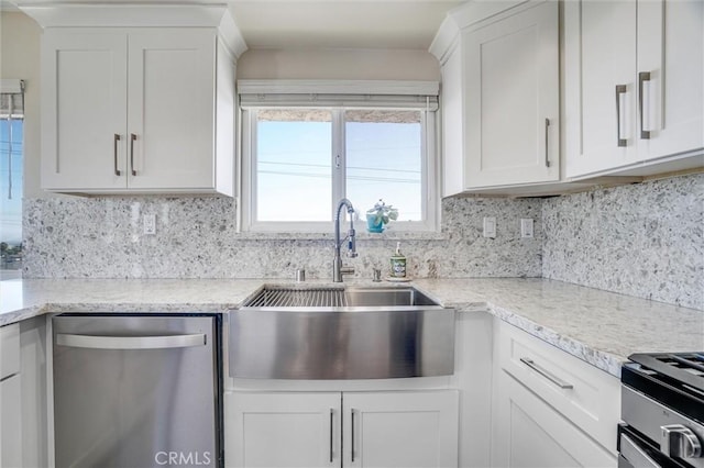 kitchen featuring white cabinets, decorative backsplash, light stone countertops, stainless steel appliances, and a sink