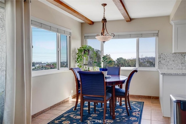 dining space with light tile patterned flooring, plenty of natural light, and beamed ceiling