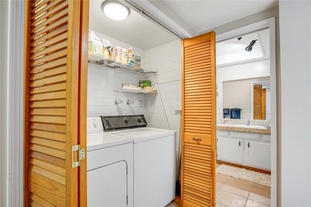 clothes washing area featuring laundry area, washer and clothes dryer, a sink, and light tile patterned flooring