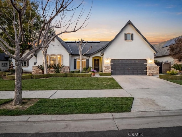 view of front of property featuring concrete driveway, a front lawn, stone siding, and stucco siding