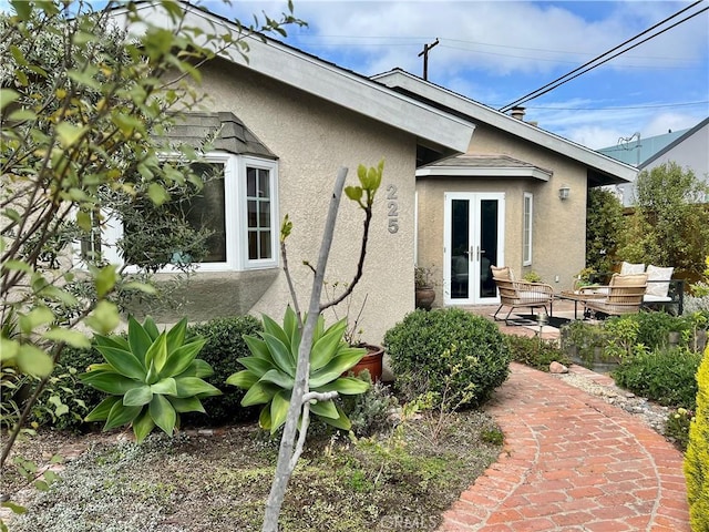 rear view of house with a patio area, french doors, and stucco siding