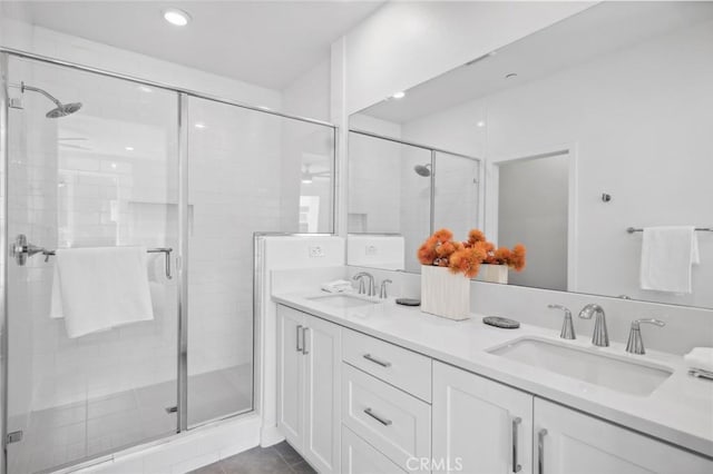 full bath with double vanity, a stall shower, tile patterned flooring, and a sink