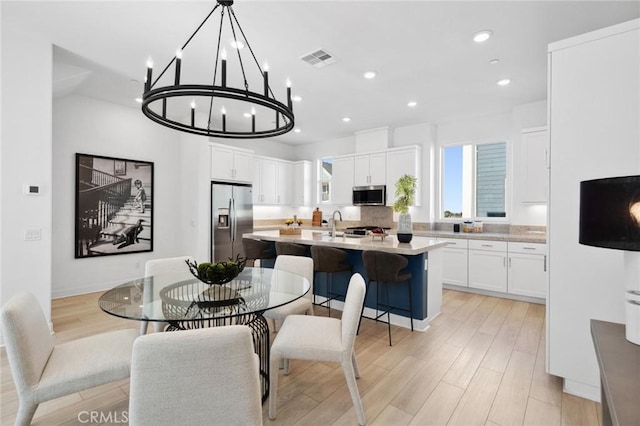 dining space with light wood finished floors, visible vents, and recessed lighting