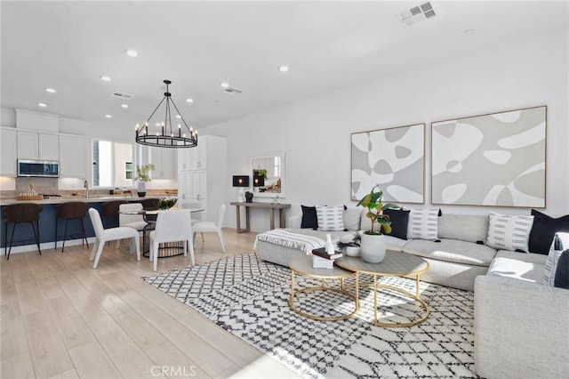 living room with light wood-style floors, visible vents, a notable chandelier, and recessed lighting