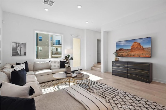 living area featuring recessed lighting, visible vents, light wood-style floors, baseboards, and stairs