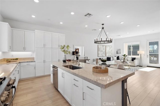 kitchen featuring light wood finished floors, stainless steel appliances, recessed lighting, a kitchen island with sink, and a sink