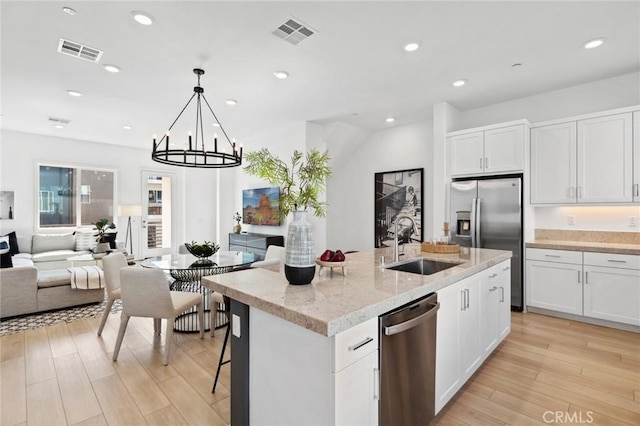 kitchen with visible vents, appliances with stainless steel finishes, open floor plan, and a sink