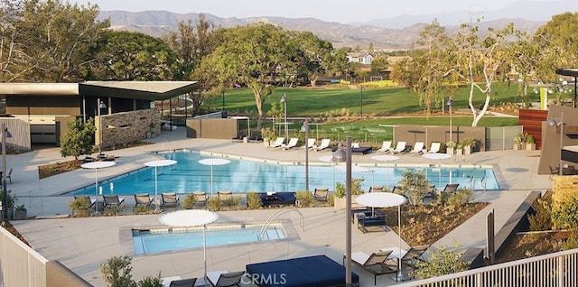 community pool featuring a patio area, fence, and a mountain view