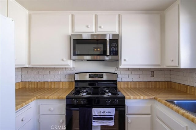 kitchen with white cabinetry, light countertops, stainless steel microwave, and gas range