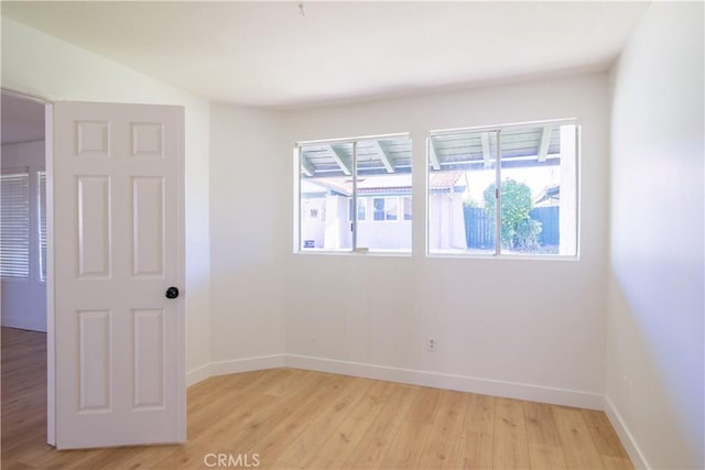 unfurnished room with baseboards, light wood-style flooring, and a healthy amount of sunlight