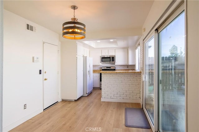 kitchen with light wood finished floors, stainless steel appliances, visible vents, white cabinetry, and a peninsula