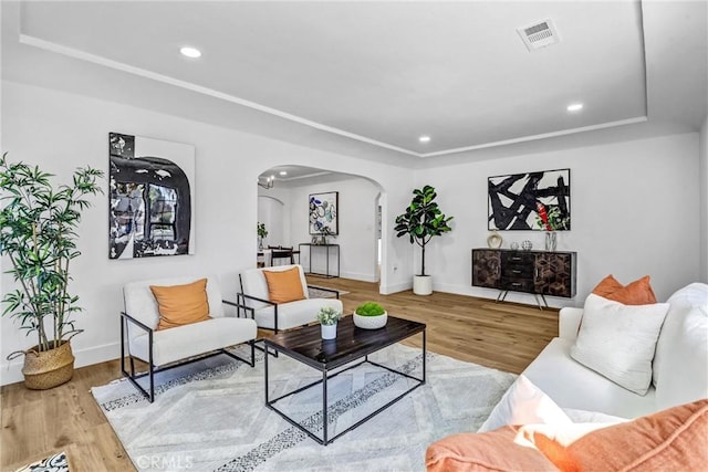 living room with arched walkways, recessed lighting, wood finished floors, visible vents, and baseboards