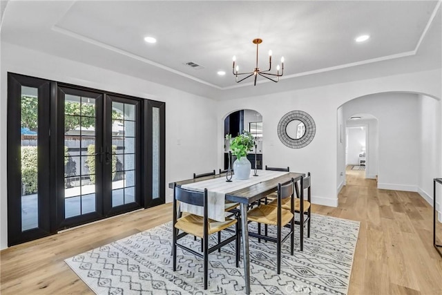 dining space with a healthy amount of sunlight, visible vents, a raised ceiling, and arched walkways