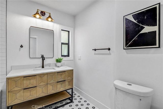 bathroom with toilet, baseboards, and vanity