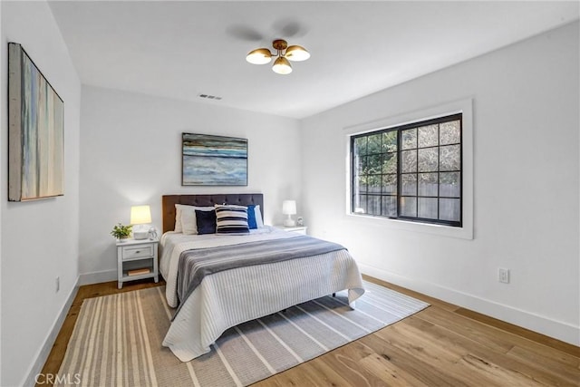 bedroom featuring baseboards, visible vents, and wood finished floors