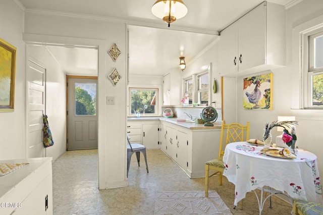 kitchen featuring a sink, white cabinets, light countertops, light floors, and crown molding