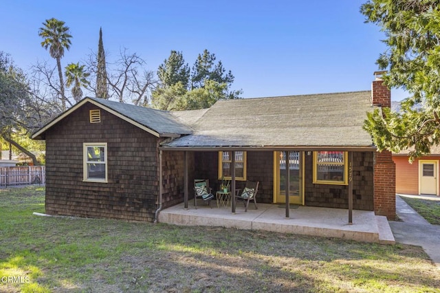 rear view of house featuring a patio area, a yard, a chimney, and fence